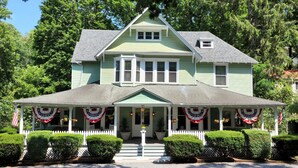 A two-story house with a front porch, a bay window, and a small attic window. - Vine Cottage Inn (Hot Springs)