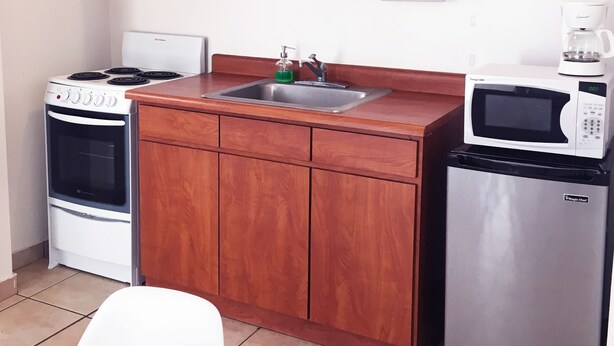 Una cocina con armarios de madera, estufa, pileta, horno microondas y refrigerador.