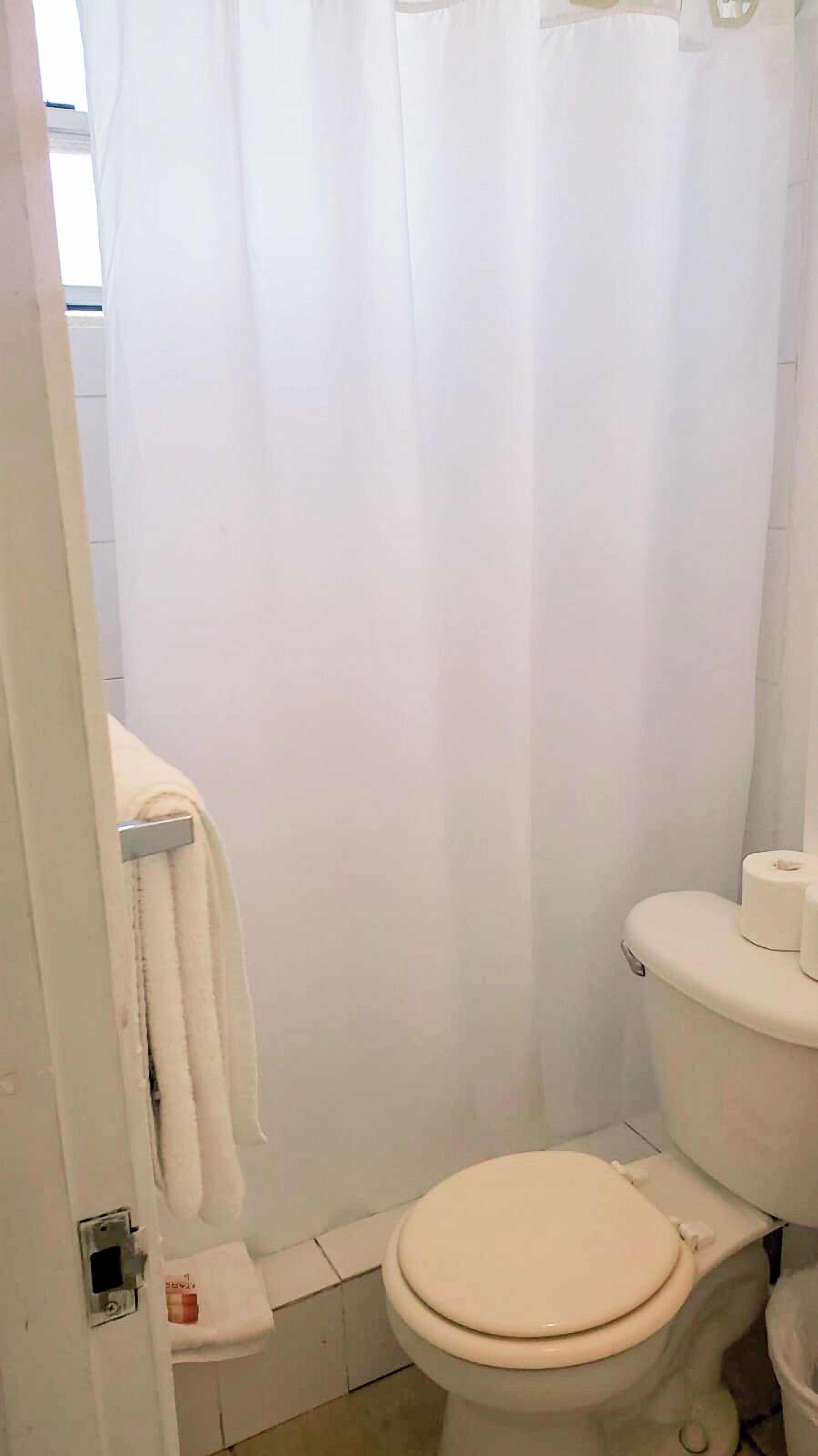 Een badkamer met een toilet, douchegordijn en handdoekhouder.
