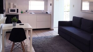 Un espace de vie compact comprenant un coin cuisine, un coin repas et un coin salon.