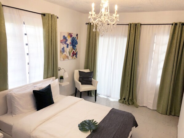 A hotel room with a bed, a chair, a desk, and a chandelier. - Aibonito Hotel 201 (Aibonito)