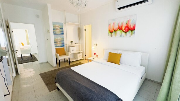 Quarto de hotel com uma cama, escrivaninha, cadeira e um quadro na parede.