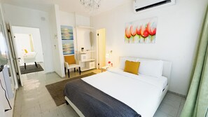 A hotel room with a bed, a desk, a chair, and a painting on the wall. - Aibonito Hotel 202 (Aibonito)