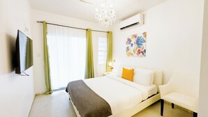 A hotel room with a bed, a bedside table with a lamp, a TV mounted on the wall, and a window with curtains. - Aibonito Hotel 203 (Aibonito)