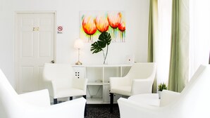 A modern living room with white furniture, a desk, and a painting of flowers. - Aibonito Hotel 203 (Aibonito)