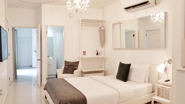 Een moderne slaapkamer met een groot bed, een kroonluchter, een airconditioner en een spiegel.