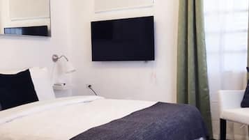 Een moderne slaapkamer met een bed, een flatscreen televisie, een nachtkastje, een lamp en een stoel.