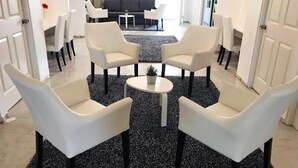 Een moderne woonkamer met een zwart-wit ruw tapijt, witte banken en een kleine ronde tafel met een plant.