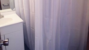 Een badkamer met een witte wastafel, een spiegel en een douchegordijn.