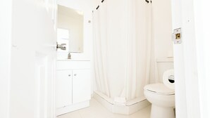 A white bathroom with a toilet, a sink, and a shower curtain.