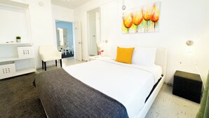 A hotel room with a large bed, a bedside table, a chair, a desk with a lamp, and a painting on the wall. - Aibonito Hotel 209 (Aibonito)