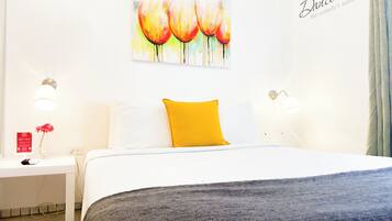 A hotel room with a bed, a nightstand, a lamp, and a painting on the wall.