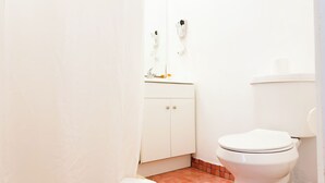 Ein kleines, sauberes Badezimmer mit Toilette, Waschbecken mit Spiegel und Handtuchhalter.