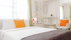 Quarto de hotel com cama, escrivaninha, cadeira e obras de arte nas paredes.