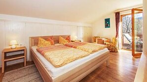 Une chambre à coucher avec un lit en bois, une table de chevet, une fenêtre avec des rideaux et une vue sur l’extérieur.