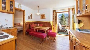 Une cuisine chaleureuse avec des meubles en bois, un coin repas avec un banc et une vue sur l’extérieur.