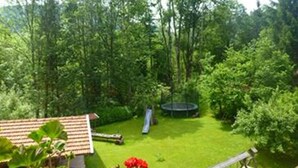 Un jardin avec un trampoline, un toboggan et un petit abri de jardin.