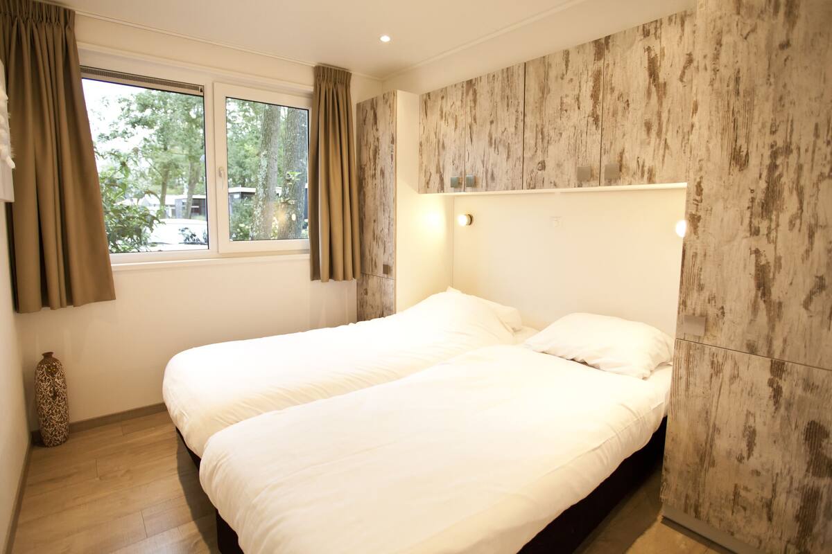 Un dormitorio con dos camas, una ventana con cortinas y una pared con diseño texturizado.