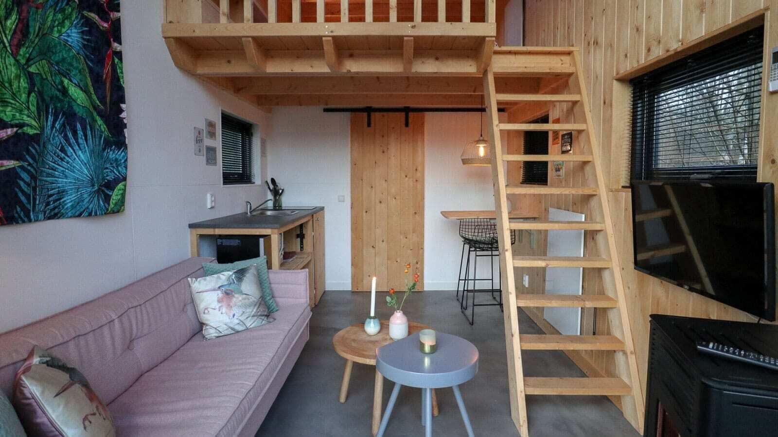 Uma sala de estar aconchegante com uma cama beliche, uma pequena cozinha, um sofá e uma televisão.