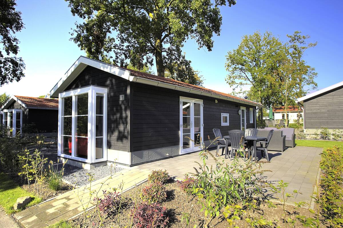 Una casa moderna con un patio, una zona de estar cubierta al aire libre y un jardín.