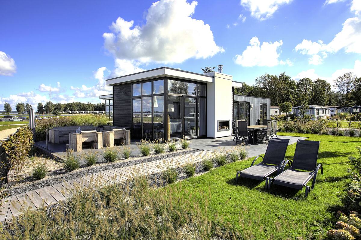 Una casa moderna con un patio, mobiliario exterior y césped.