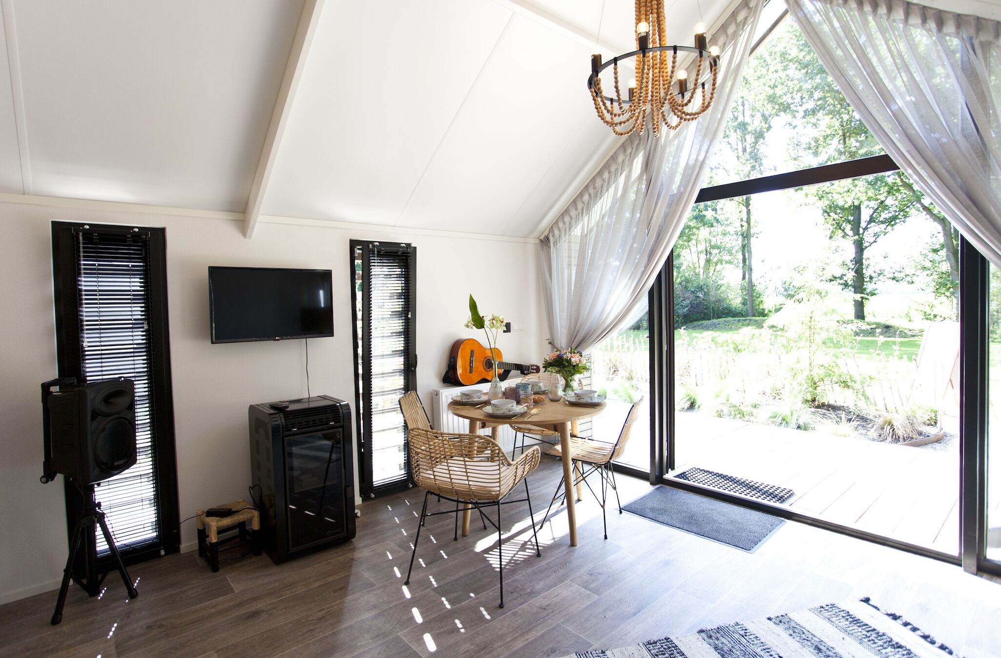 A dining area with a table, chairs, a television, and a guitar.