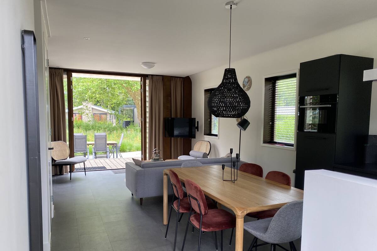 Un comedor moderno con una mesa y sillas de madera, un sofá y un televisor montado en la pared.
