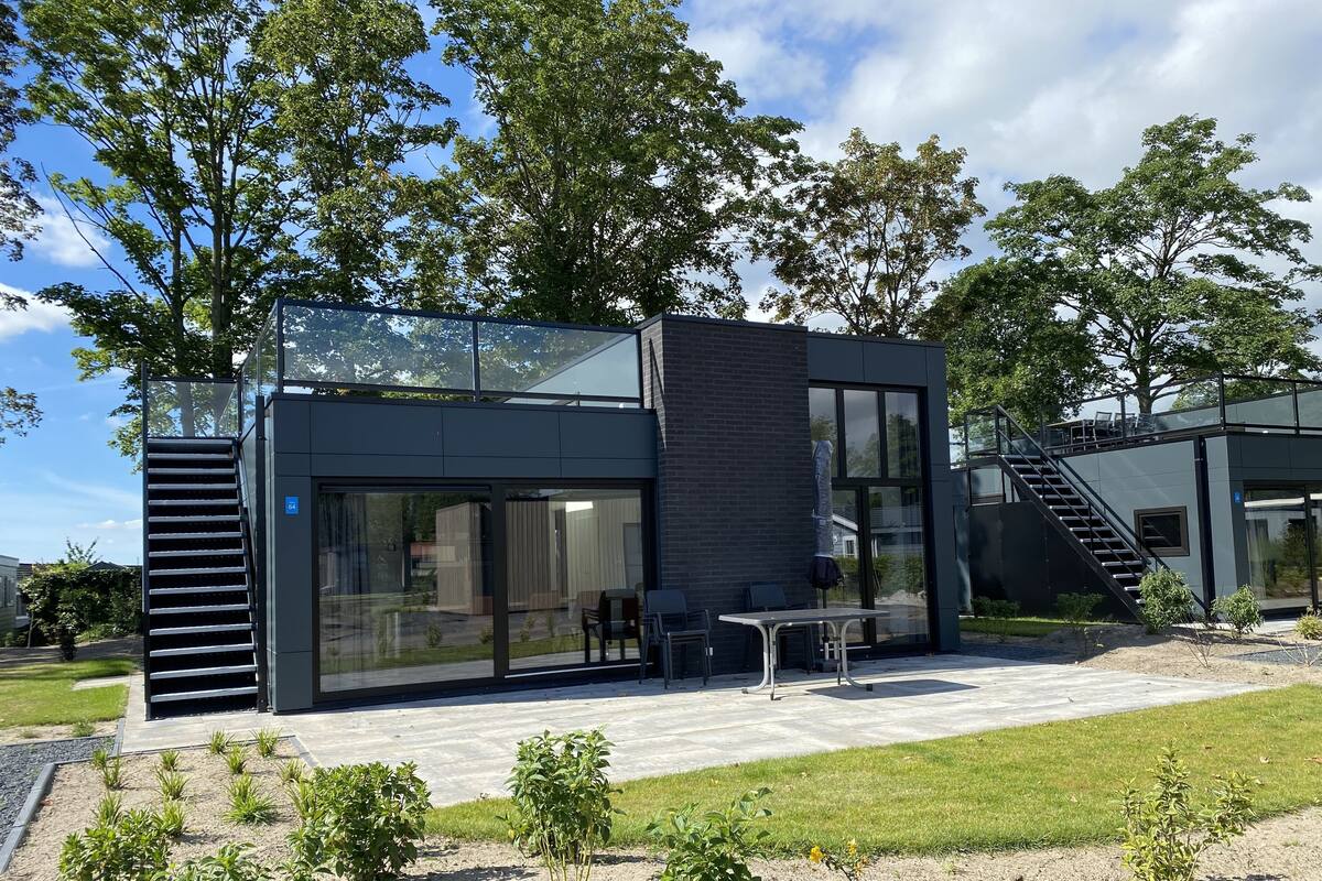 Un edificio moderno con fachada de vidrio, asientos al aire libre y una escalera que conduce a un nivel superior.