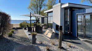 A modern house with a patio, outdoor furniture, and a view of the sea. - EuroParcs Bad Hoophuizen (Hulshorst)