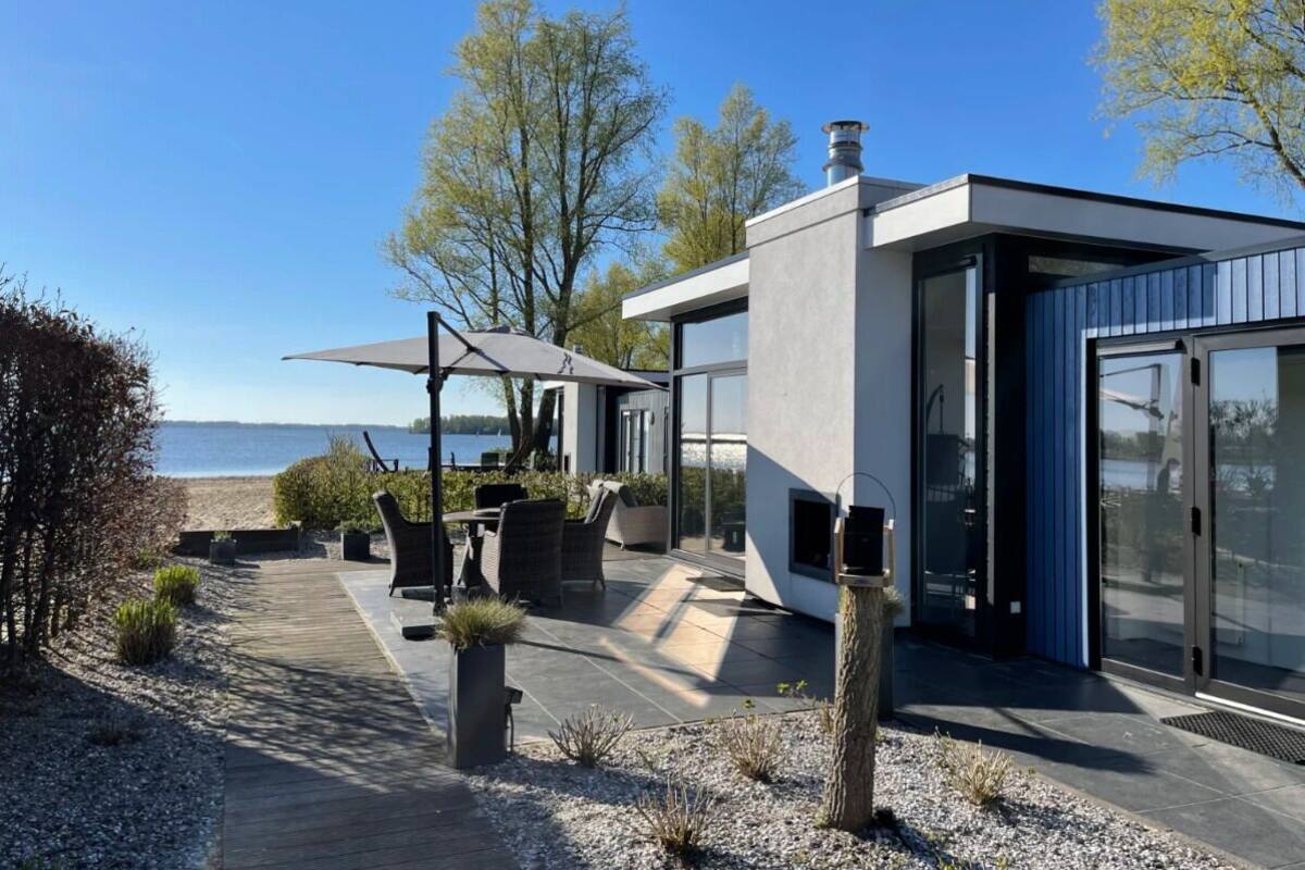 Una casa moderna con un patio, mobiliario exterior y vistas al mar.