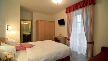Una camera d'albergo con un letto grande, una scrivania, uno specchio e una televisione.