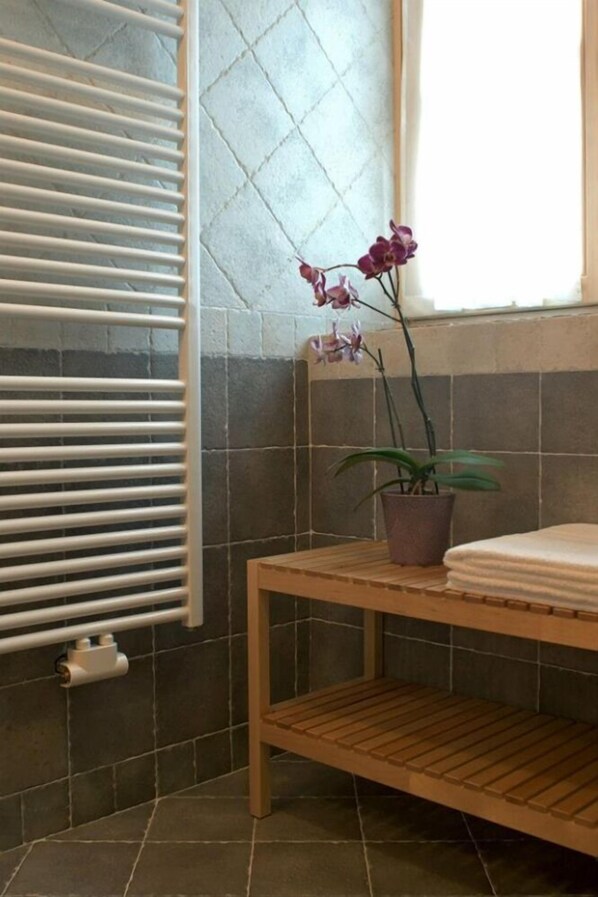 A bathroom with a wooden bench, a potted orchid, and a towel on the bench. - B&B Sissi (Commezzadura)