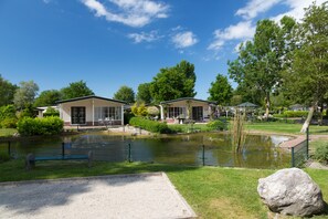Un parque con un estanque, bancos y una gran roca.