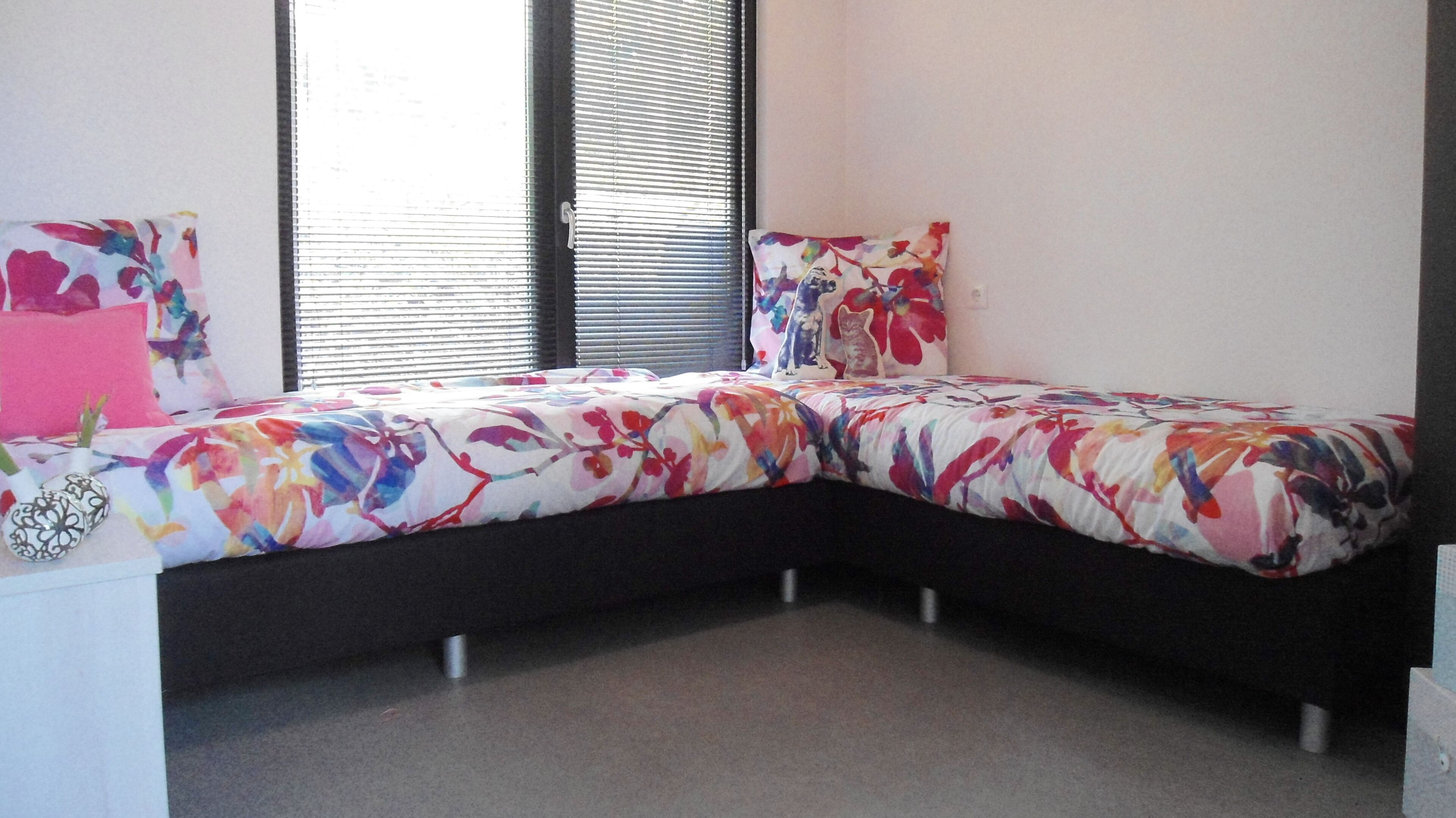 Un dormitorio con una cama curvada, una mesita de noche y una ventana con persianas.