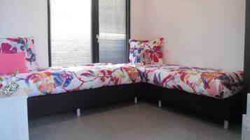 Un dormitorio con una cama curvada, una mesita de noche y una ventana con persianas.