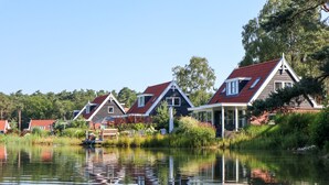 A row of houses with red roofs and white trim, situated beside a calm lake. - EuroParc De Zanding (Otterlo)