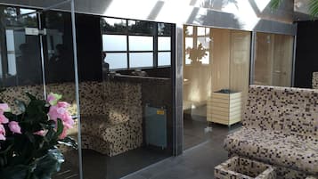 Relax in a stylish seating area with a sofa and ottoman, separated from a cozy reading nook by a glass partition.