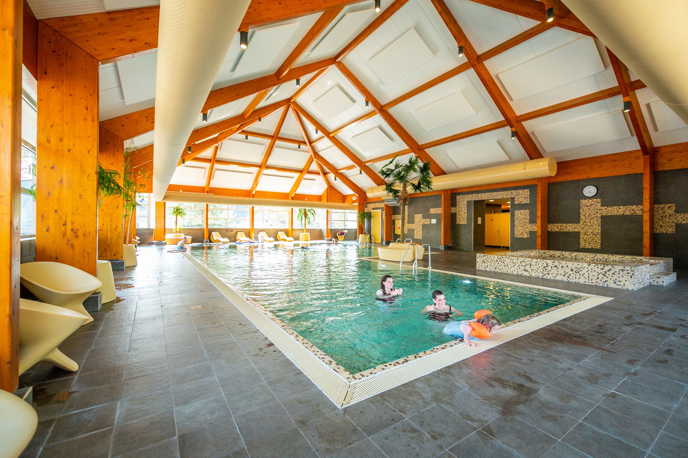 Een binnenzwembad, ligstoelen bij het zwembad