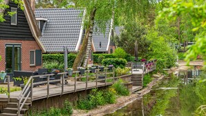 A wooden bridge over a canal with a row of houses on one side. - EuroParc De Zanding (Otterlo)