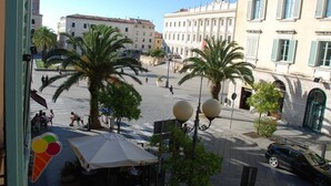 Ett torg med palmer, ett kafé och historiska byggnader.