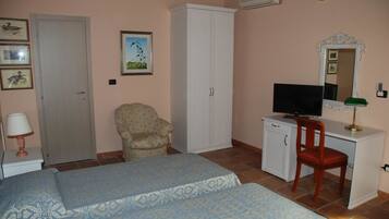 Une chambre avec deux lits, une armoire, un bureau avec une télévision, une chaise et une lampe.
