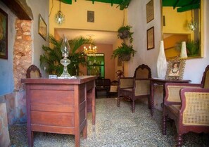 Une pièce chaleureuse avec un bureau en bois, des chaises en osier, un lustre et un miroir.
