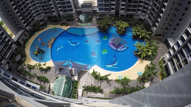 Um edifício alto com uma grande piscina com motivos de golfinhos, rodeado por palmeiras e áreas de lazer.