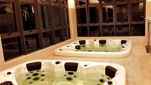 Espaço de spa com duas banheiras de hidromassagem e área de estar com guarda-corpo de vidro.