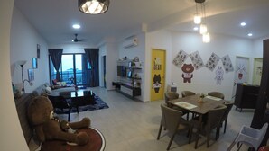 Uma sala de estar com sofá, uma mesa de jantar com cadeiras, um urso de pelúcia e uma porta amarela decorada com desenhos de ursos.