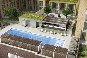 Une piscine sur le toit, agrémentée de chaises longues, un jardin luxuriant aménagé sur le toit et un bâtiment moderne doté de grandes fenêtres.