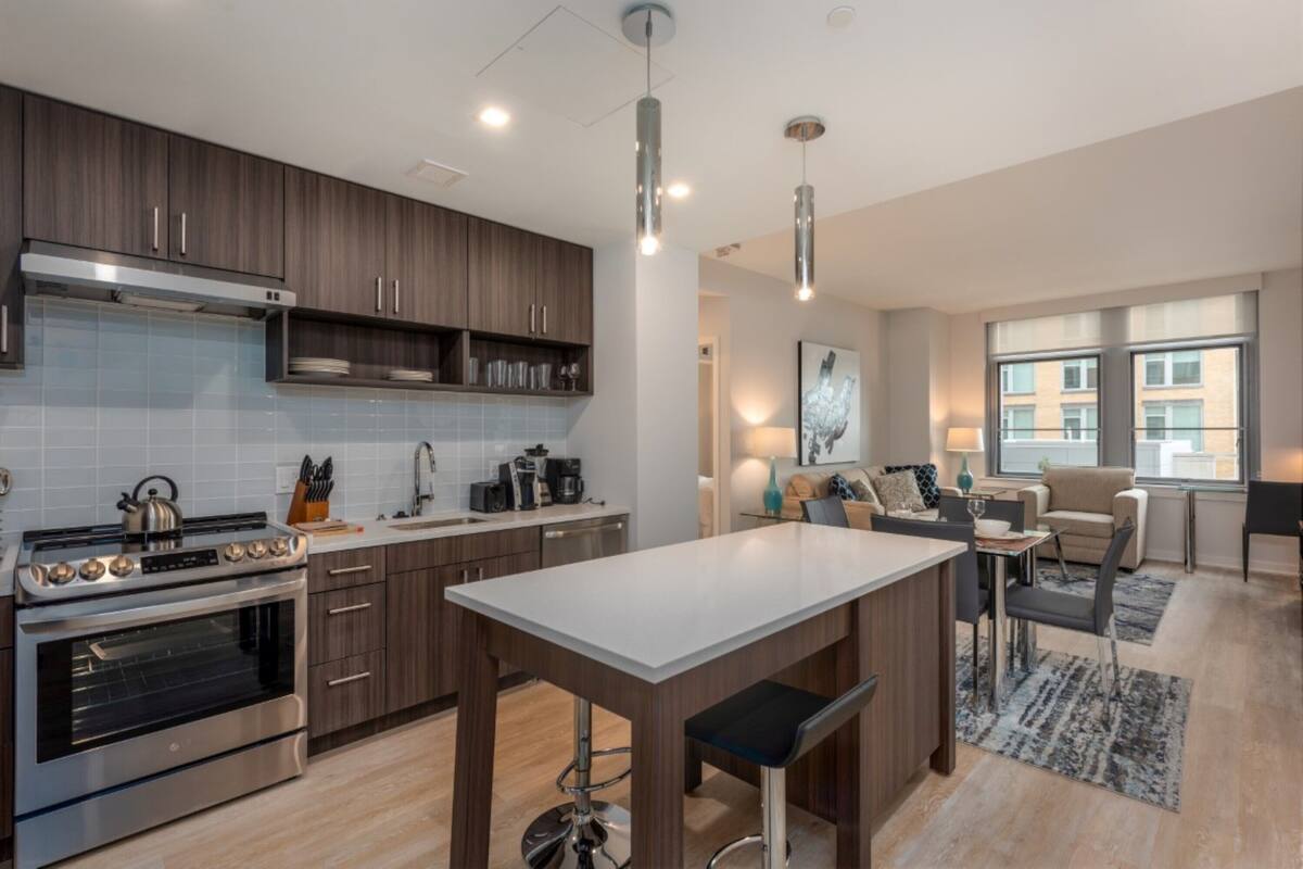 A modern kitchen with a central island, stainless steel appliances, and wooden cabinets.