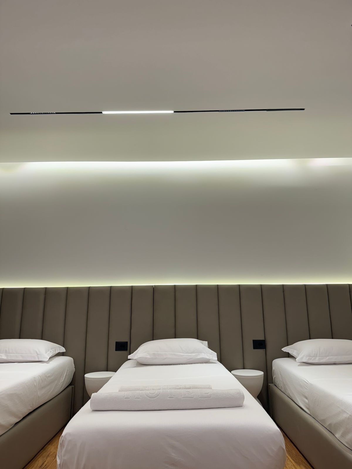 Una habitación de hotel moderna con una cama grande, dos mesitas de noche y una lámpara fijada a la pared.