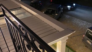 A balcony with a metal railing overlooking a street at night.