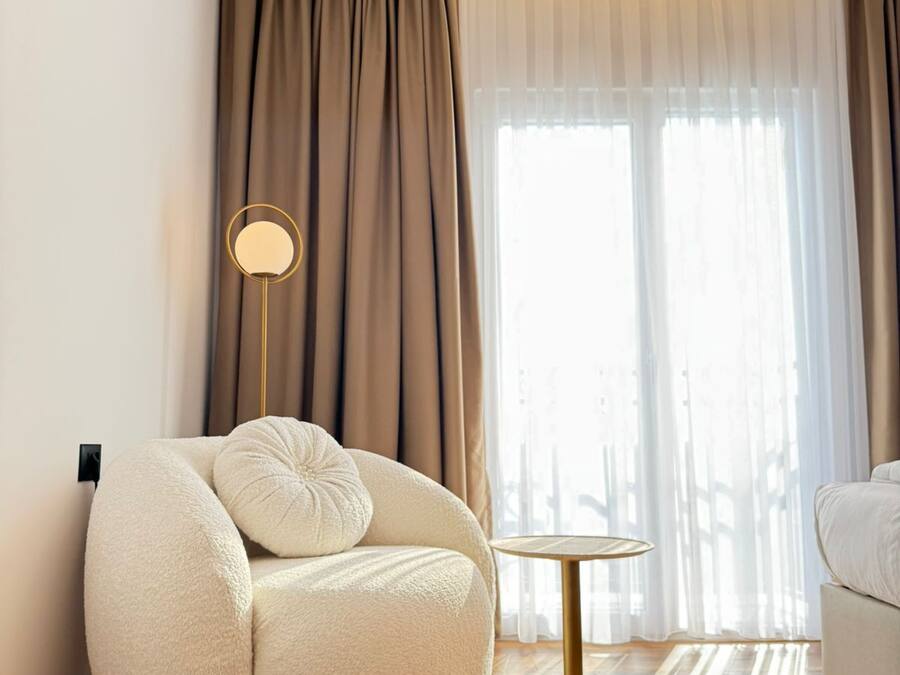 A modern living room with a round, plush sofa, a small side table, and a floor lamp.